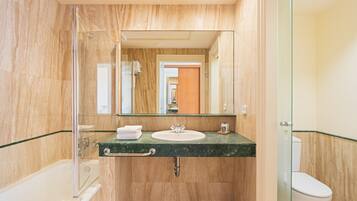 Une salle de bain avec une douche à parois de verre, un lavabo avec un plan de toilette en marbre et des toilettes.