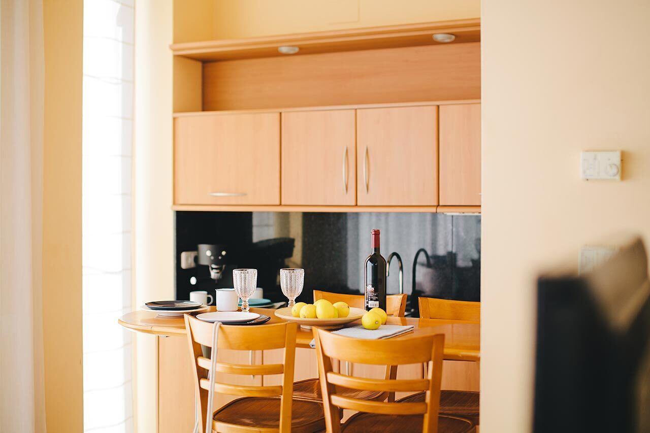 Une cuisine moderne avec des meubles en bois, une table à manger ronde et des chaises. On peut voir des assiettes, des verres et une bouteille de vin sur la table.
