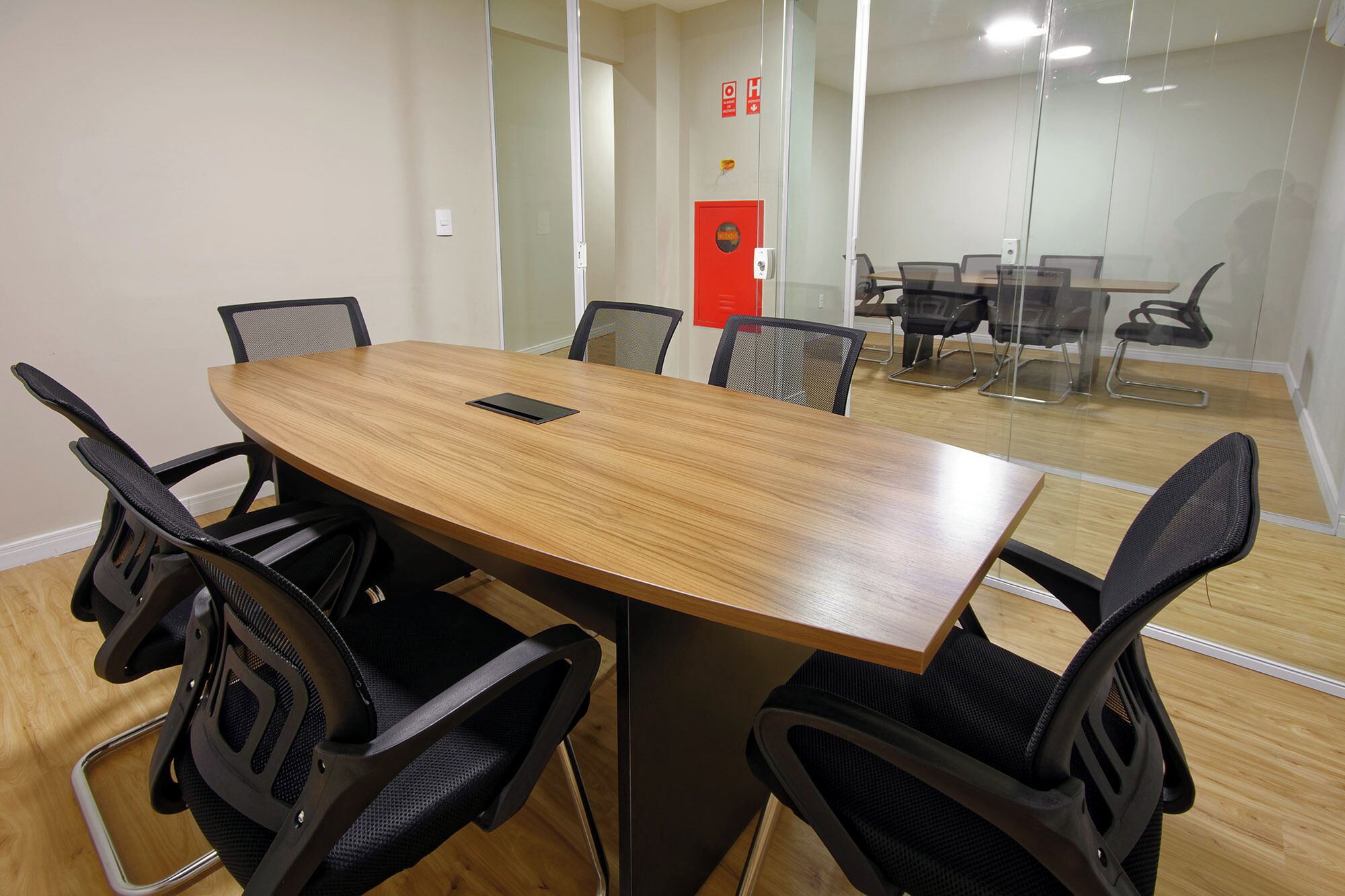 A conference room with a wooden table and six black chairs.