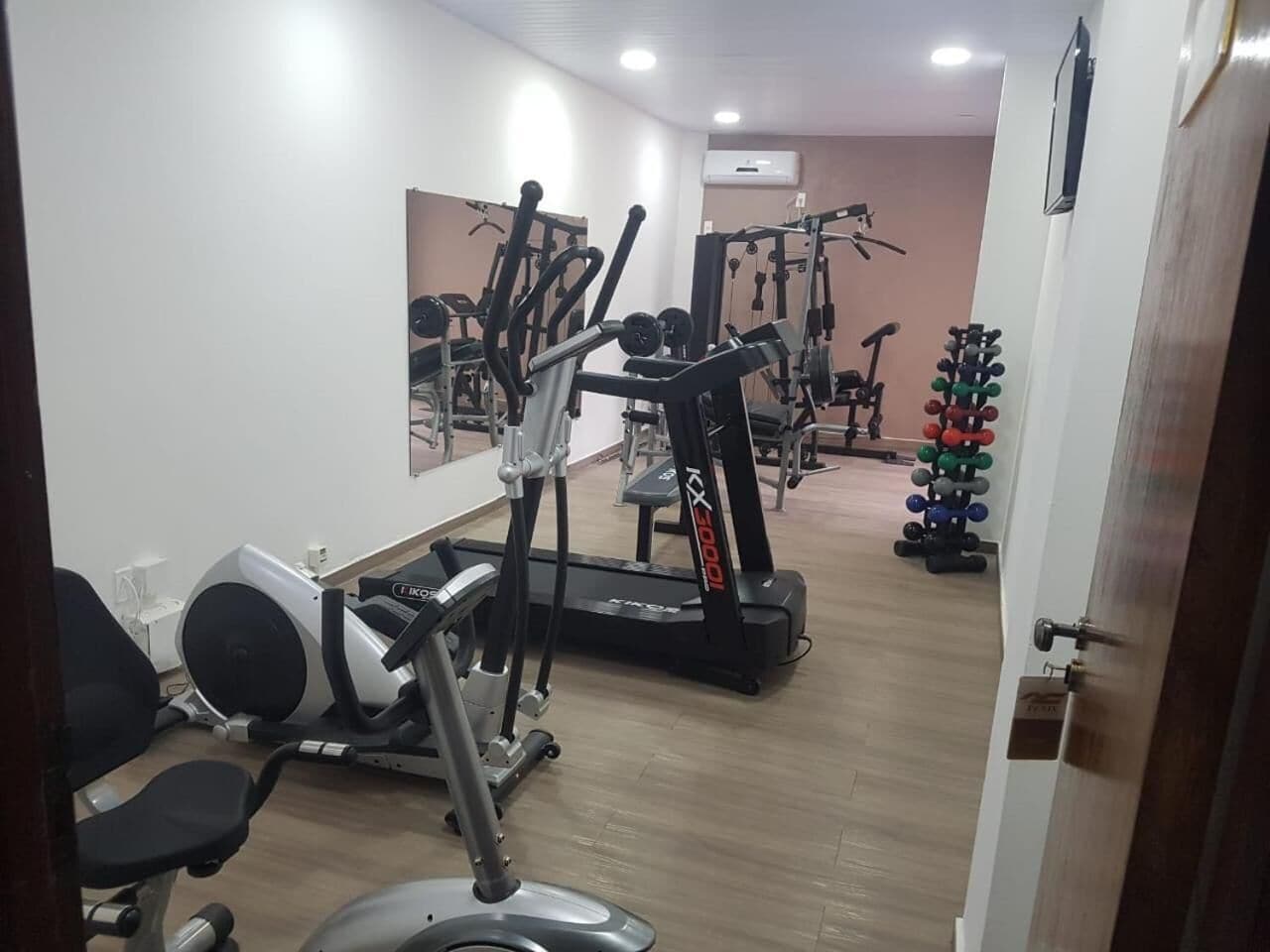 Une salle de sport équipée de machines de cardio, de matériel de musculation et d’un miroir mural.