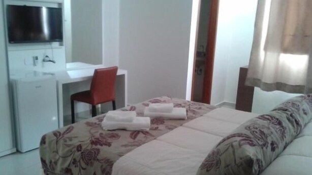 A hotel room with a bed, a desk, and a chair. - Hotel Cristal (Turmalina)