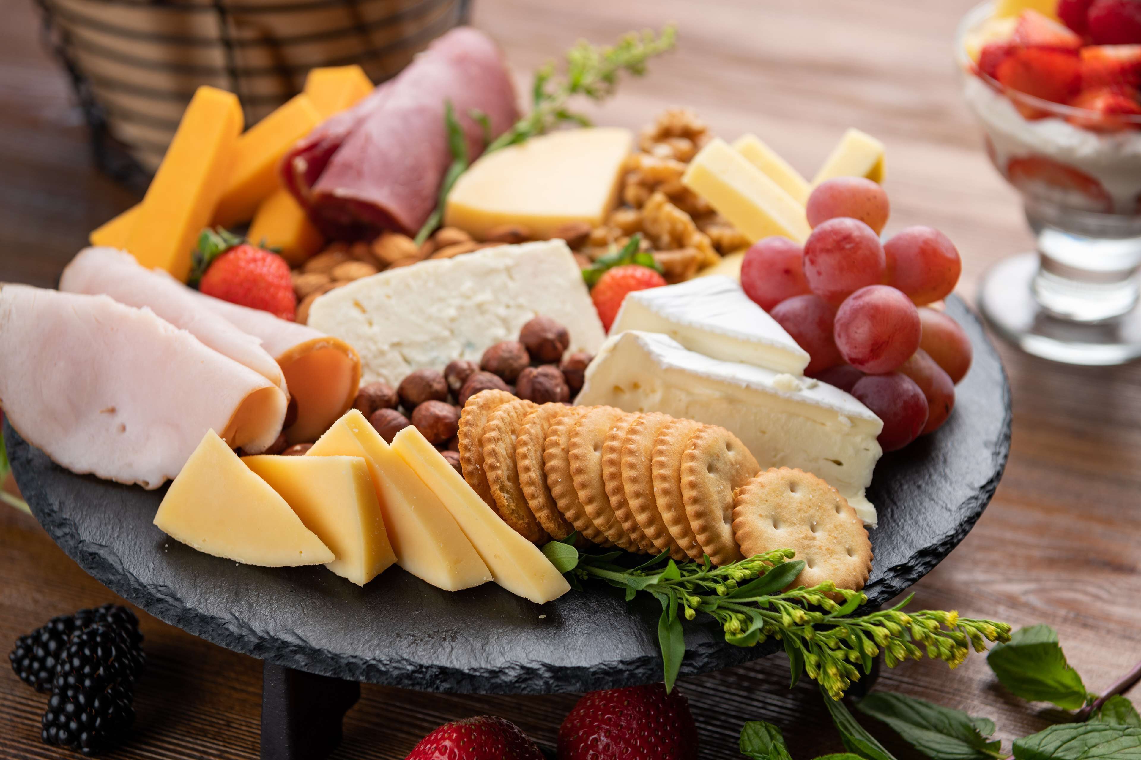 Una tabla de embutidos con diversos quesos, carnes, frutas y frutos secos.
