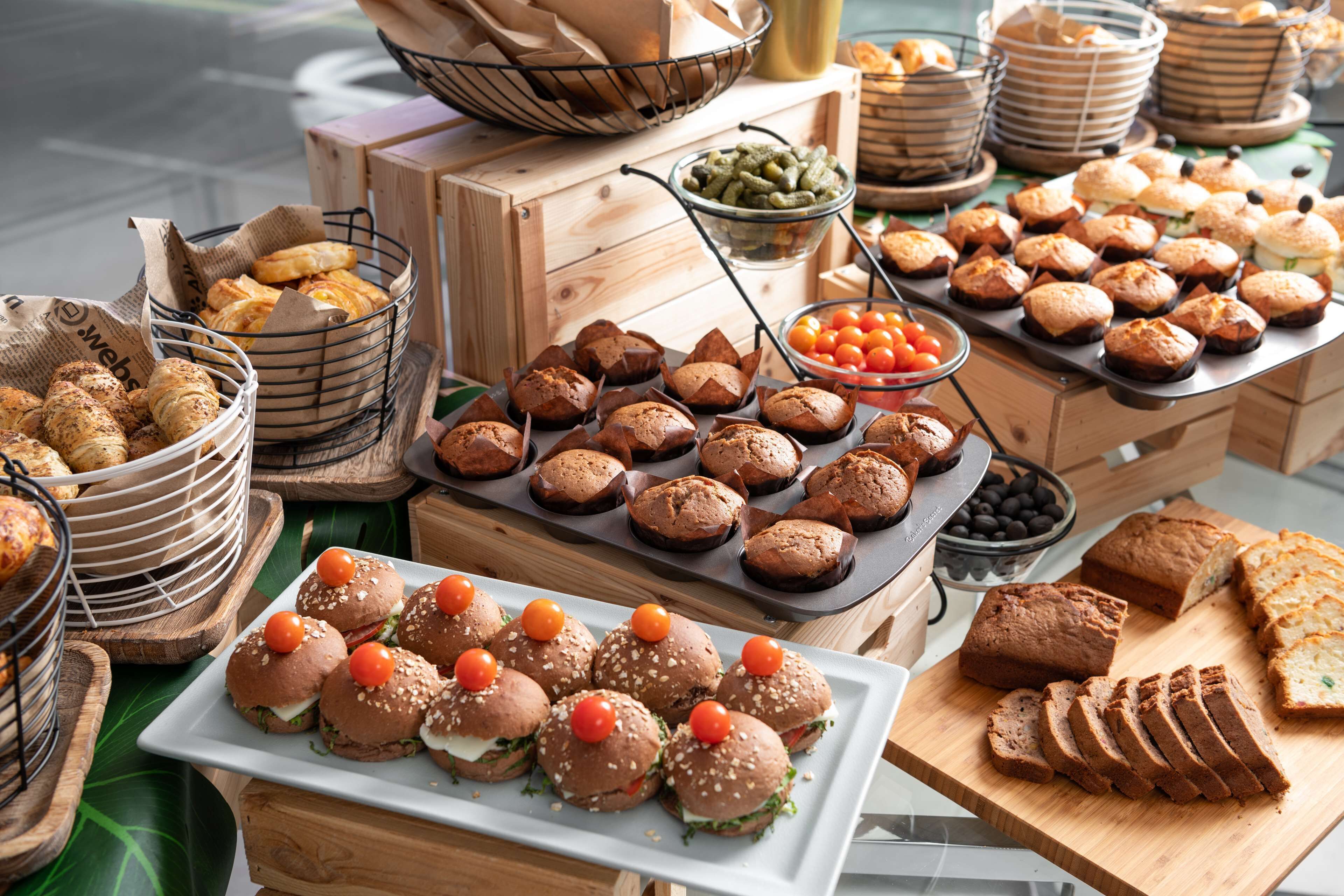 A variety of baked goods including muffins, bread, and pastries displayed on wooden crates and trays.