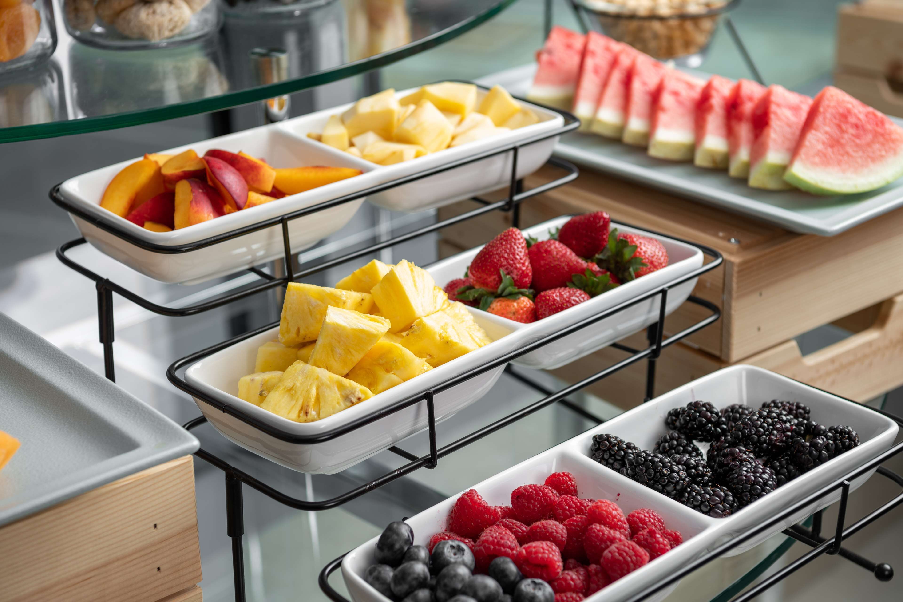 Ein Buffet mit verschiedenen Früchten, darunter Ananas, Erdbeeren, Blaubeeren und Wassermelone.