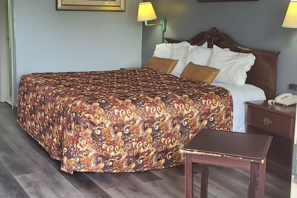 Una habitación de hotel con una cama grande, dos lámparas de noche, una mesita de noche de madera y una pequeña mesa.
