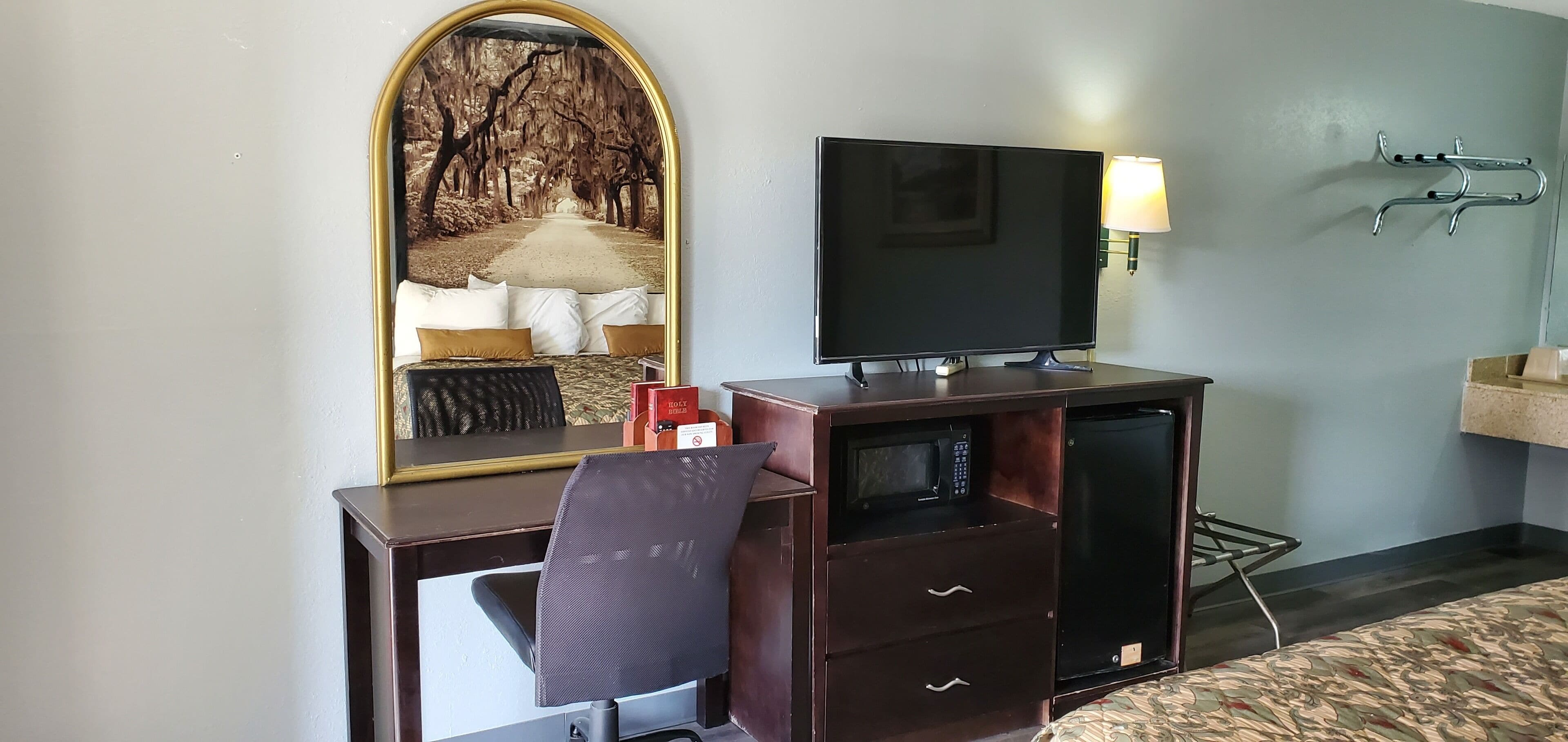 Habitación de hotel con escritorio, silla, televisión y espejo, con vistas panorámicas.