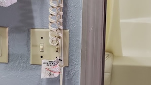 A hair dryer mounted on a wall with a power outlet below it. - Palmetto Inn (Estill)