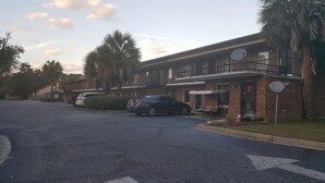A two-story motel with a parking lot. - Palmetto Inn (Estill)