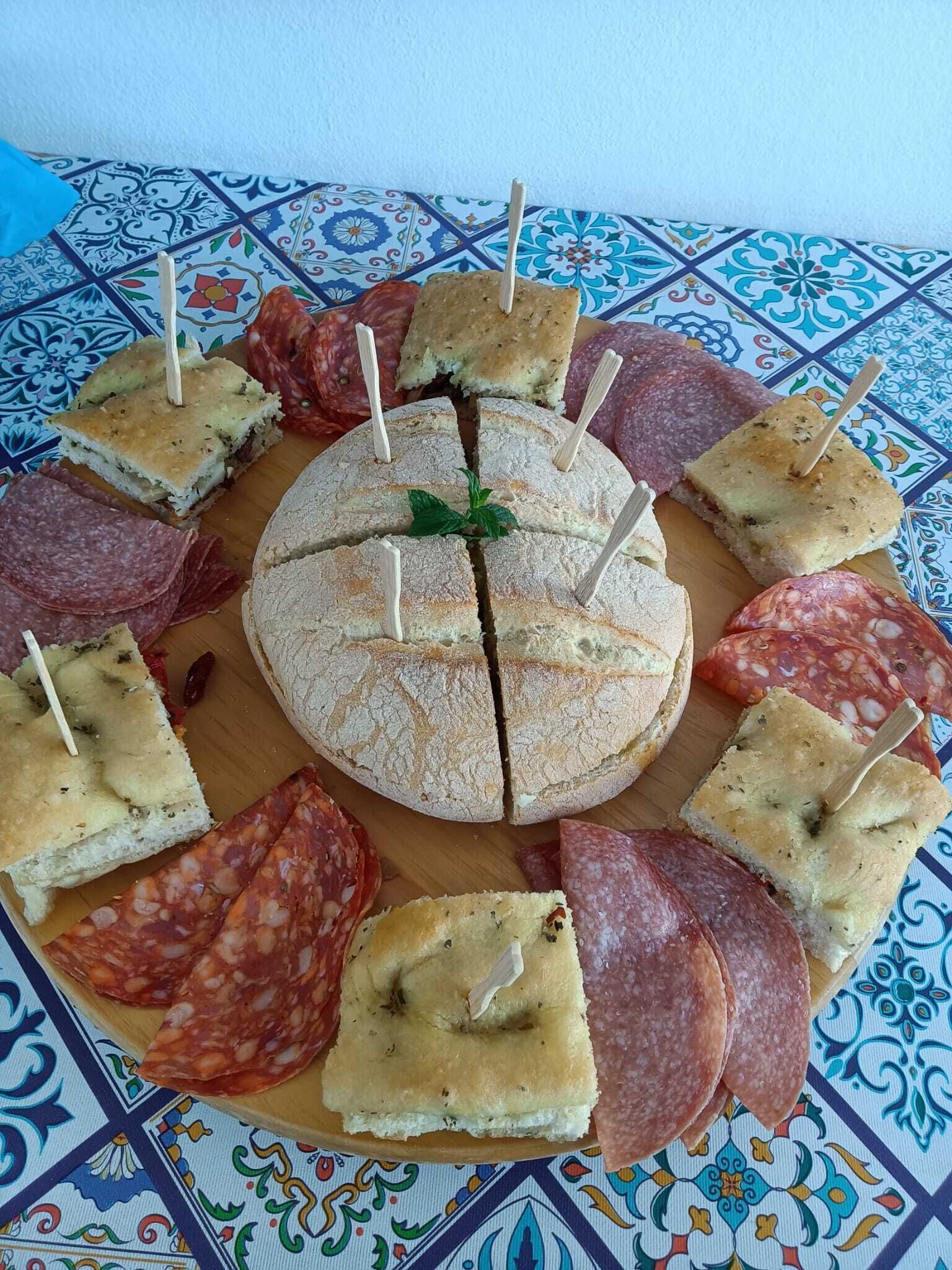 A round platter with various types of cured meats and bread slices arranged around it.