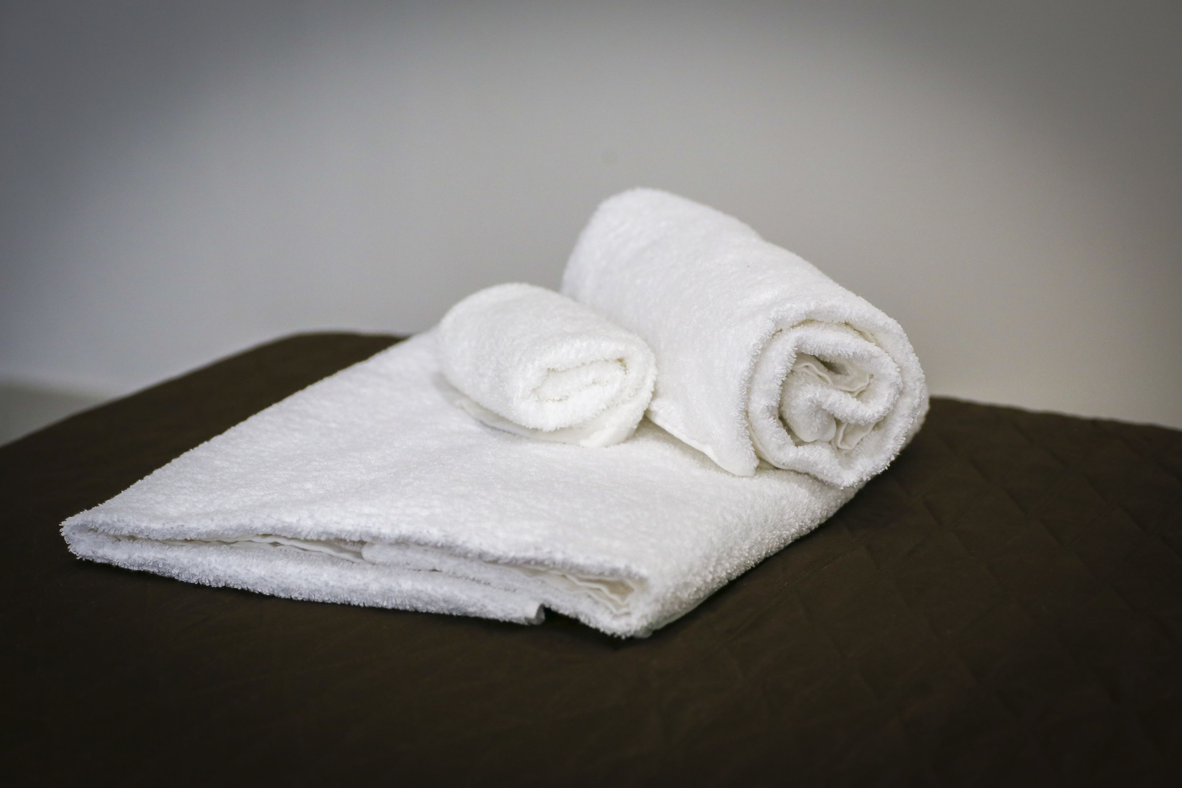 A neatly folded white towel on a dark brown surface.
