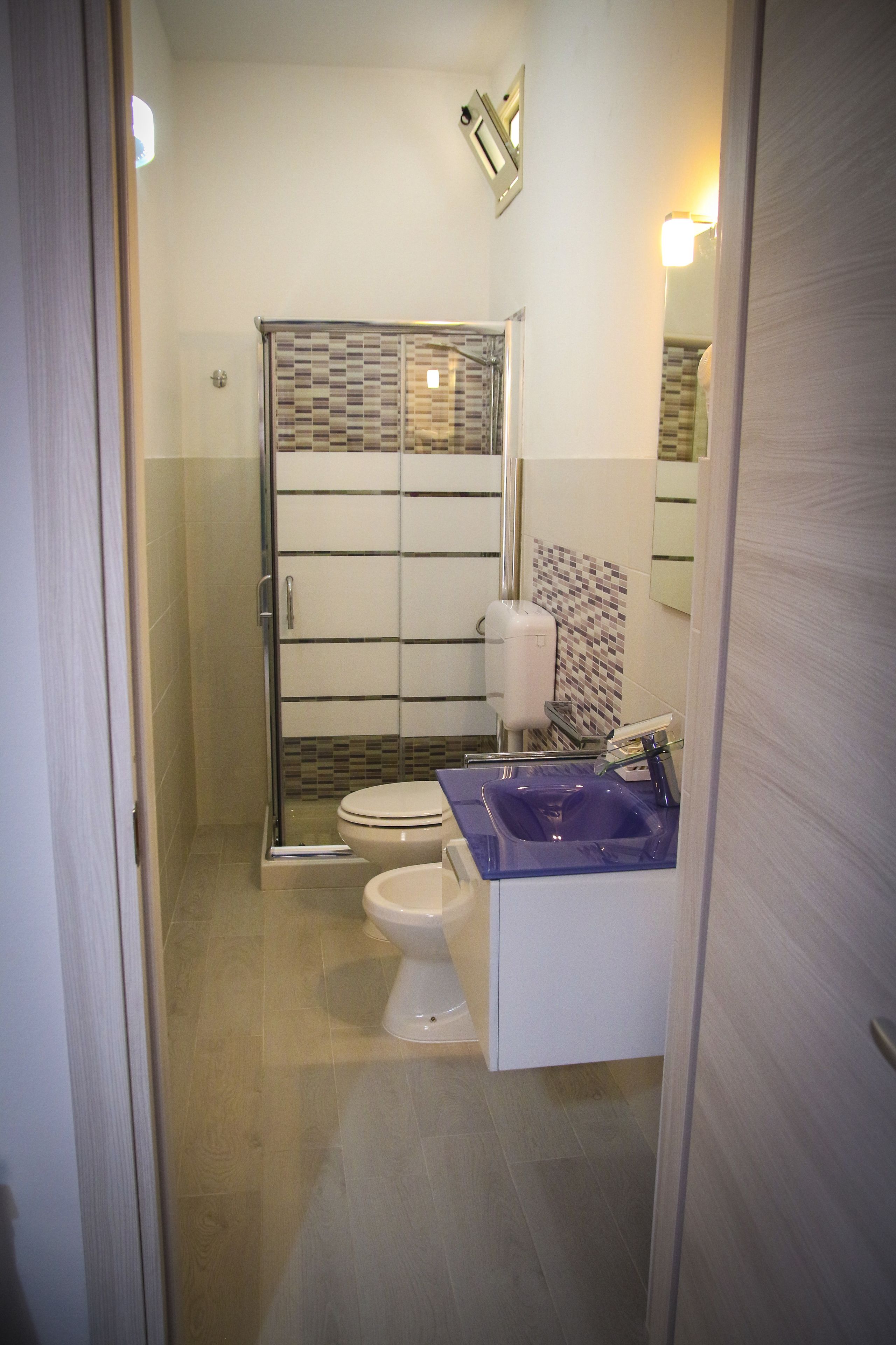 A bathroom with a shower enclosure, a toilet, and a sink.