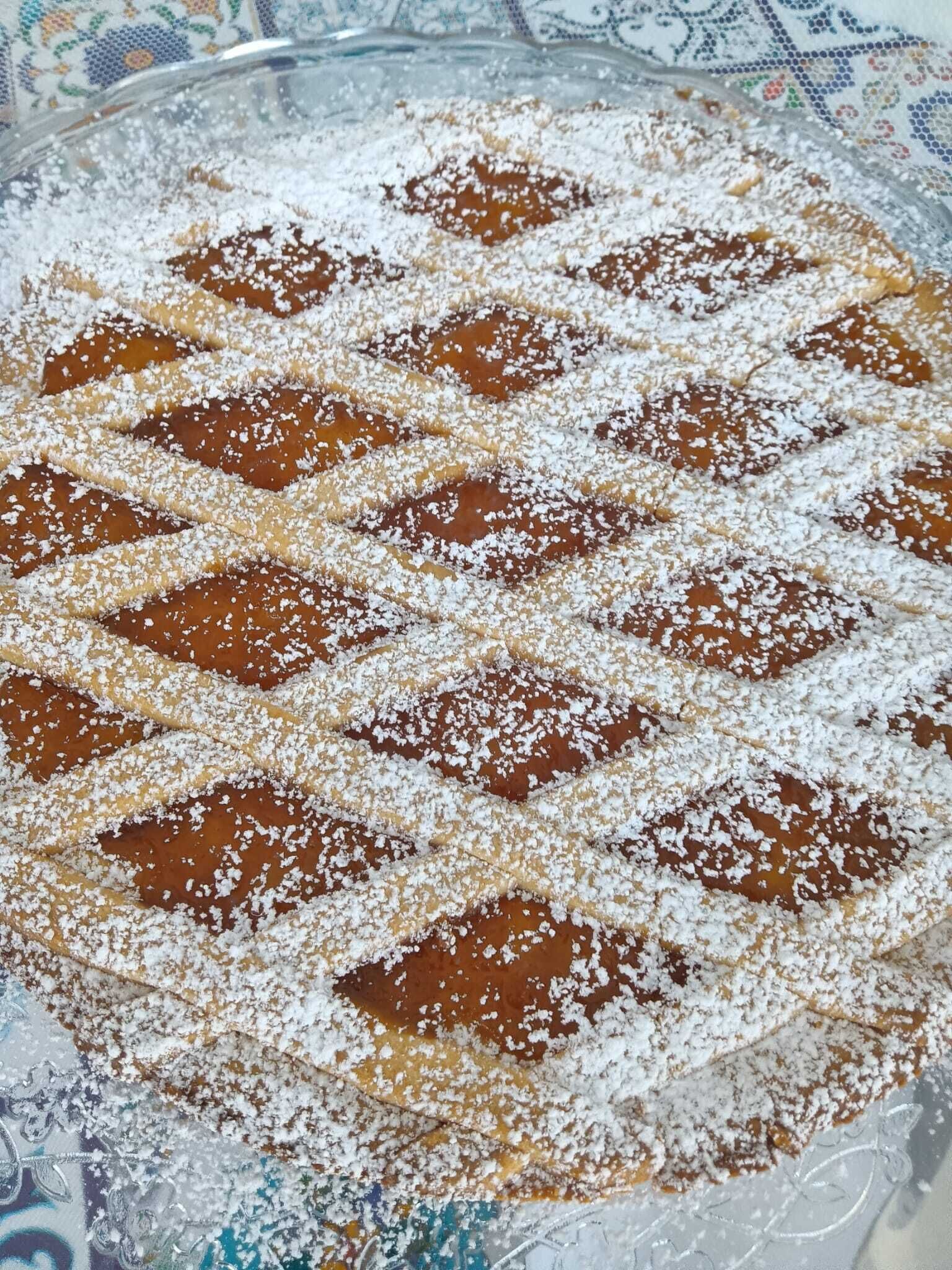 Un postre con costrado y azúcar glas sobre un mantel estampado.