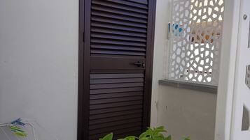 A dark brown door with horizontal slats, a white wall, and a white decorative fence.