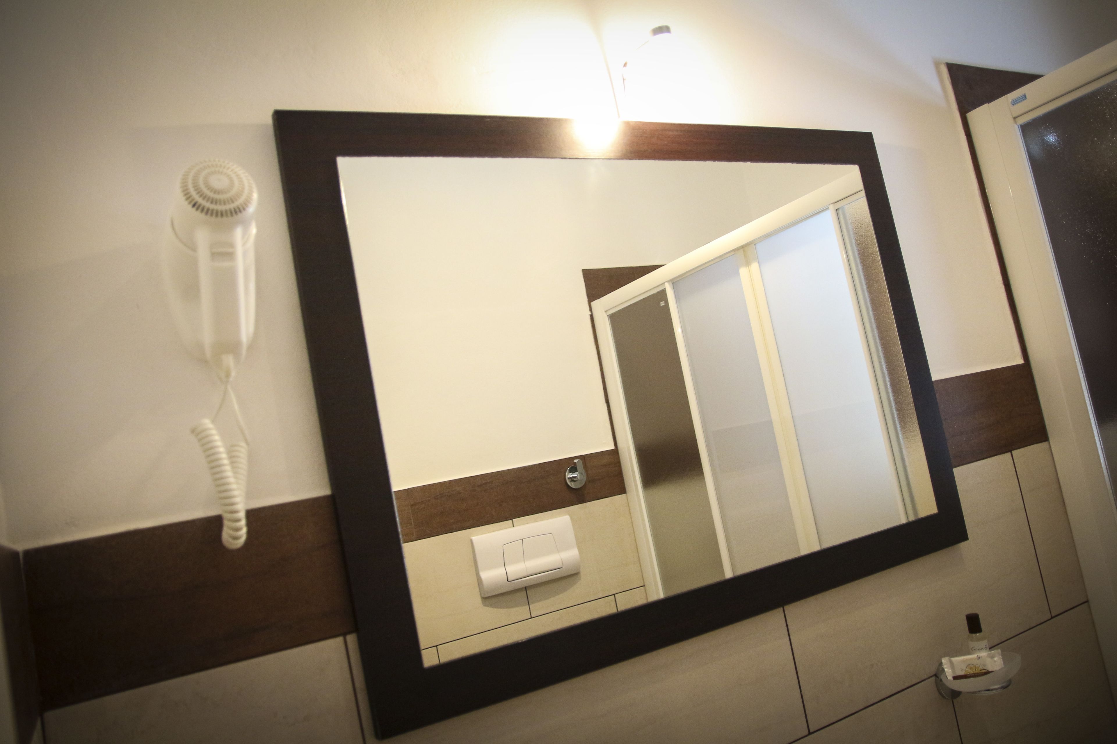 A bathroom with a large mirror, a hairdryer, and a towel dispenser.