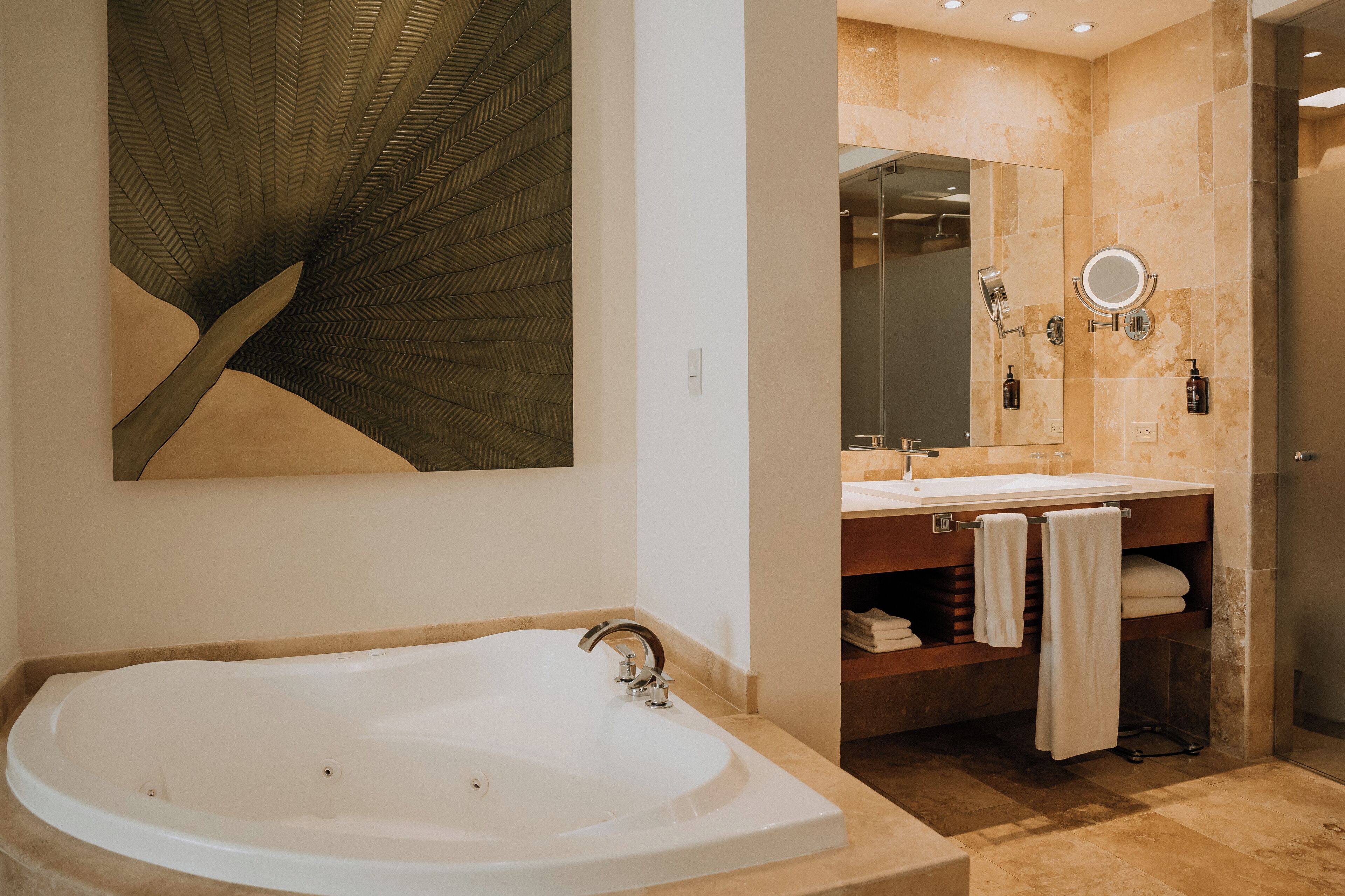 Un baño moderno con una bañera independiente, un espejo grande y un tocador con toallero.