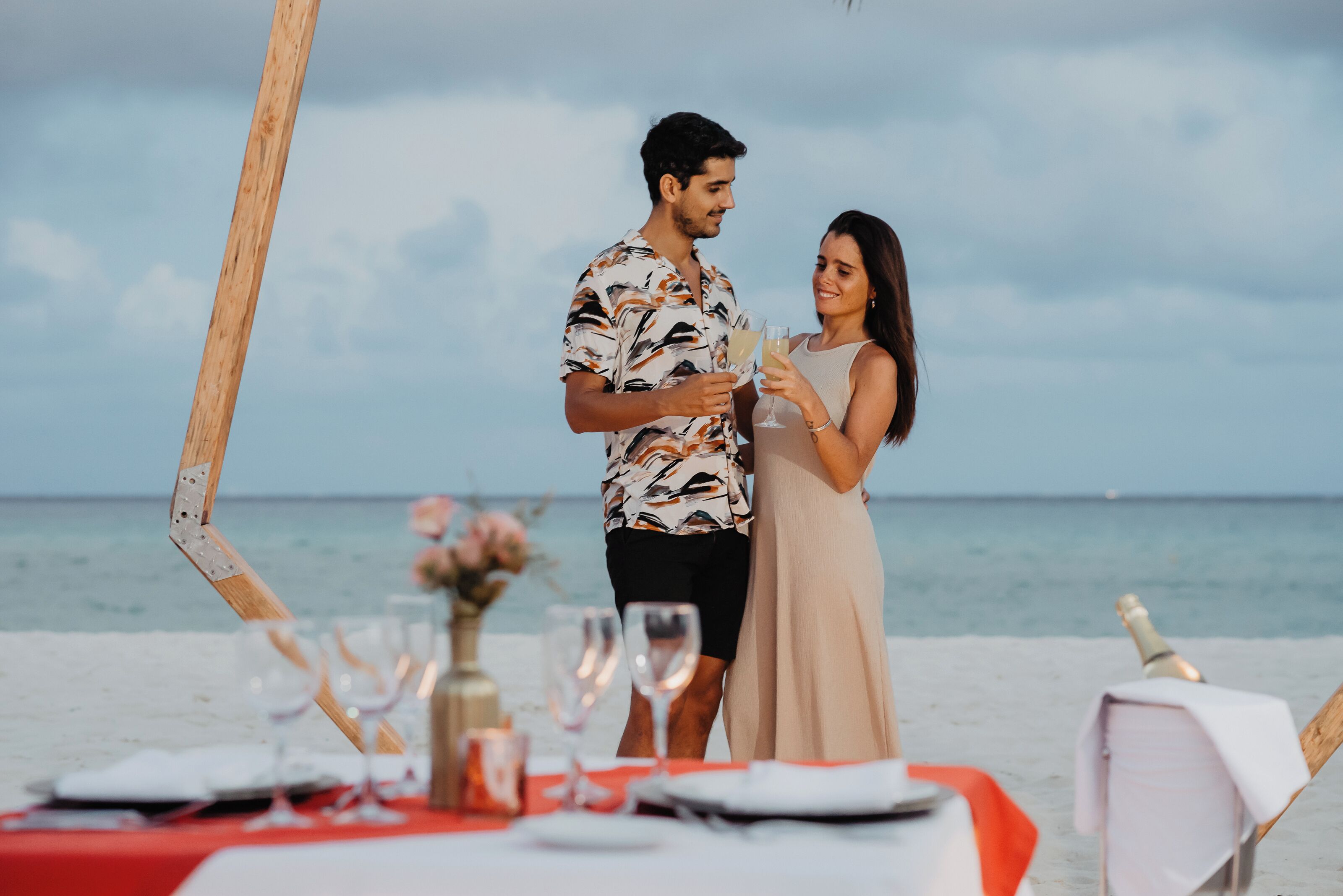 A couple standing at a beachside table with a view of the ocean.