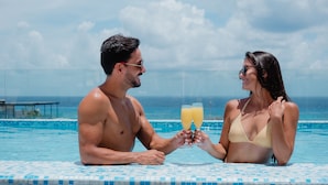Una pareja en una piscina con vistas al océano.