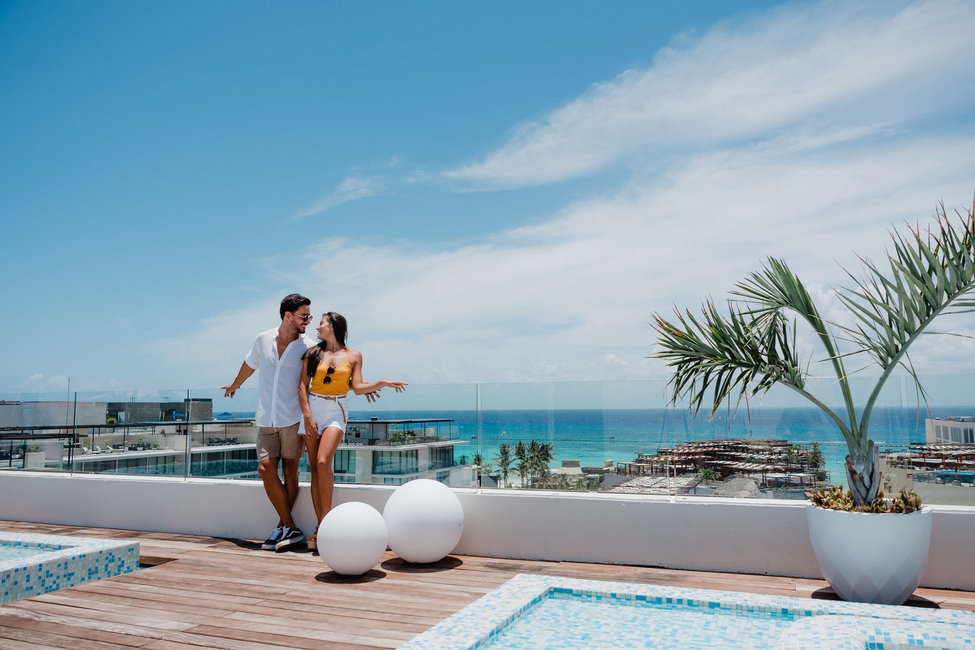 A rooftop pool area with a clear view of the ocean and distant buildings.