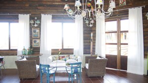A dining area with a wooden ceiling, a chandelier, wicker furniture, and a view through a large window. - Los Origenes (Concordia)