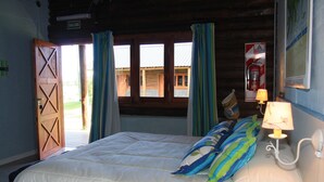 A bedroom with a bed, curtains, a window, a wall-mounted lamp, and a door. - Los Origenes (Concordia)
