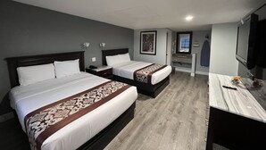 A hotel room with two beds, a desk with a mirror, and a TV.