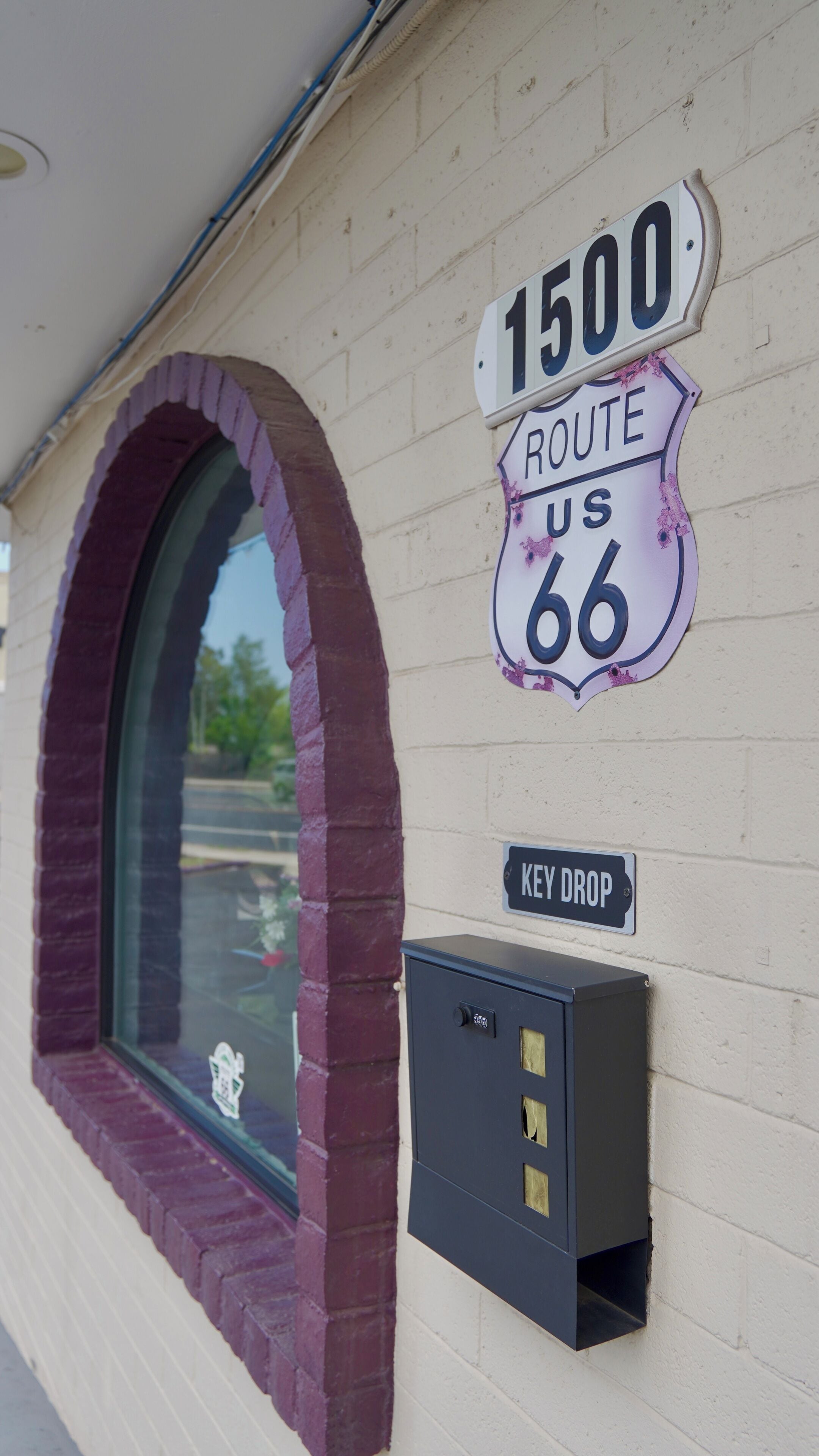 A building facade with a window, a wall-mounted mailbox, and a sign indicating Route 66.