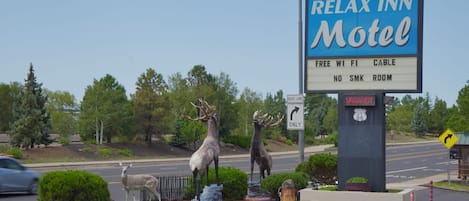 A motel sign with deer statues, a 'VACANCY' sign, and a 'RIGHT LANE ONLY' sign.