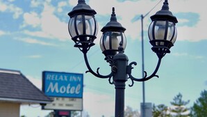 A street lamp with three globes, a motel sign, and a red pickup truck in the background.