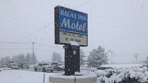 A snow-covered sign for the Relax Inn Motel with amenities listed. - Relax Inn Motel (Flagstaff)
