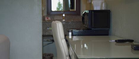 A kitchenette with a microwave, a trash can, and a chair.