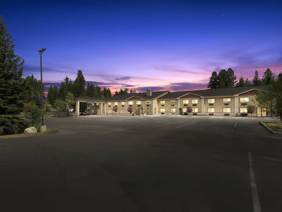 A hotel with a large parking lot and a row of rooms.
