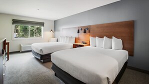 A hotel room with two beds, a large window, a wooden headboard, and a bedside table with lamps. - Third Street Inn (McCall)