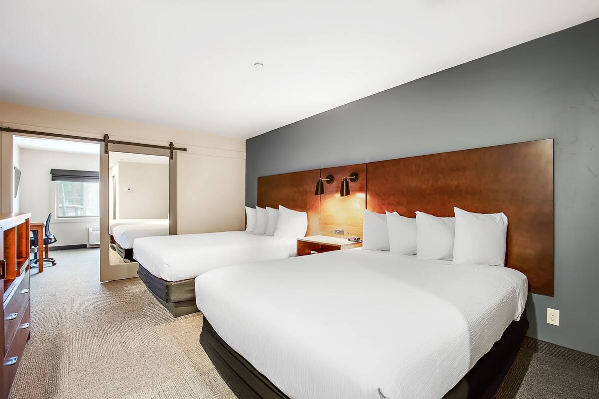 A hotel room with two beds, a desk, and a chair.