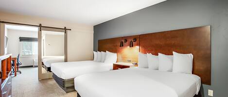 A hotel room with two beds, a desk, and a chair.