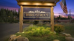 A sign for the "Third Street Inn" with a mountain silhouette, an American flag, and a well-lit entrance. - Third Street Inn (McCall)