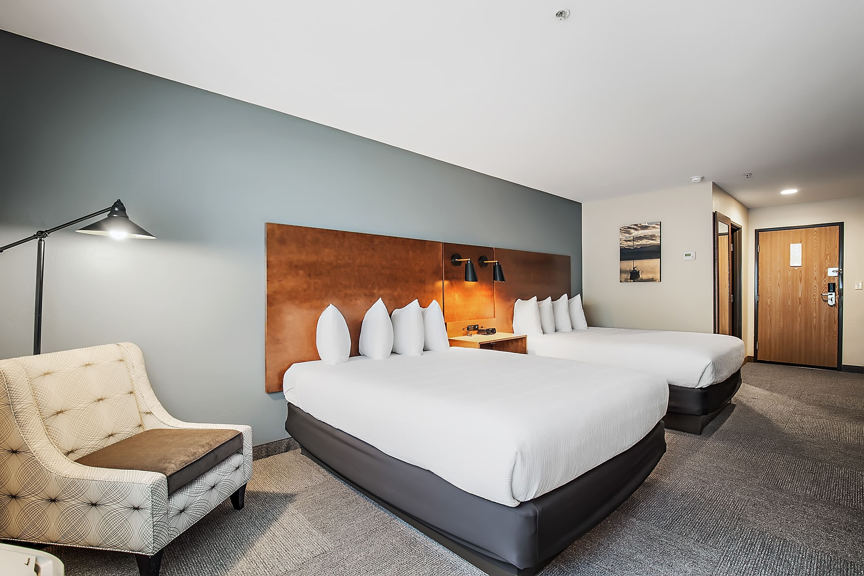Una habitación de hotel con una cama grande, una mesita de noche, una lámpara y una silla.