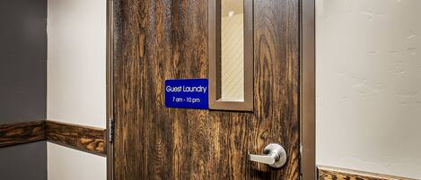 A wooden door with a sign indicating guest laundry hours.