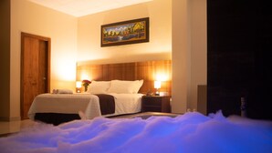 A hotel room with a bed, bedside lamps, a painting on the wall, and a wooden door.
