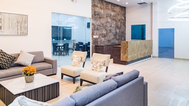A modern lobby with a sofa, armchairs, a coffee table, and a reception desk.