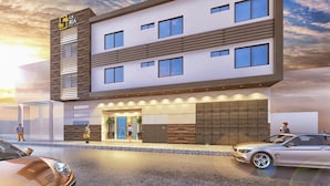 A modern hotel with a two-story structure, a prominent entrance, and a parking area with cars.
