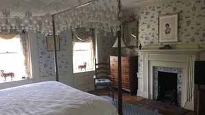 Un dormitorio con cama de dos plazas, un aparador de madera, una silla y una chimenea.