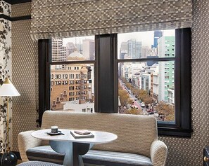A room with a large window, a sofa, a round table, and a lamp. - San Francisco Proper Hotel (San Francisco)