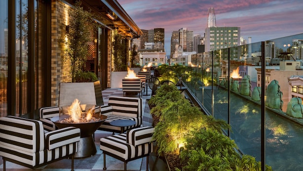 Una terraza en la azotea con una chimenea, asientos y vistas al horizonte urbano.