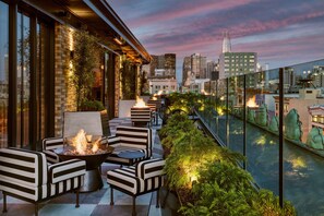 A rooftop terrace with a fire pit, seating, and a view of the city skyline. - San Francisco Proper Hotel (San Francisco)