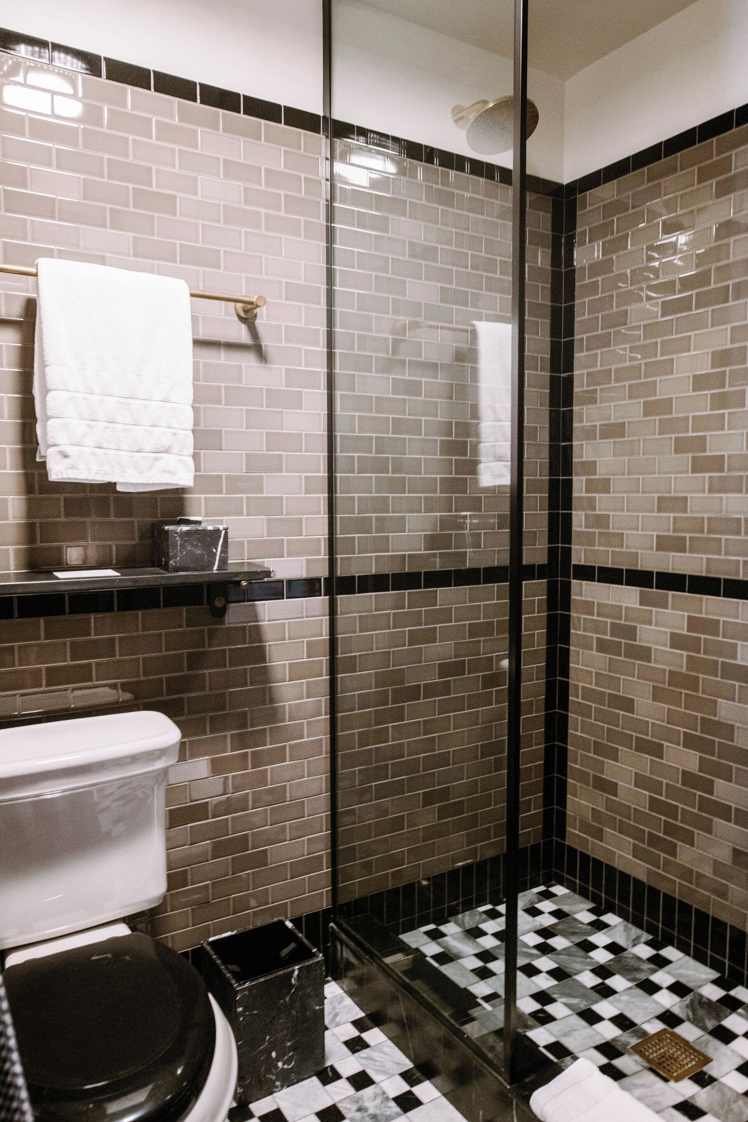 Ein Badezimmer mit Toilette, Waschbecken und Duschbereich, wobei Wände und Boden mit Fliesen versehen sind.