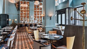 Un restaurante con piso a cuadros, varias mesas y sillas para comer, y una zona de bar al fondo.