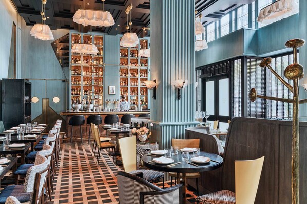 A restaurant with a checkered floor, multiple dining tables, and chairs, with a bar area in the background. - San Francisco Proper Hotel (San Francisco)