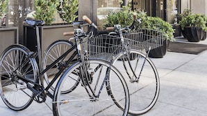 Entrada de un hotel con un cartel que dice "PROPER HOTEL", bicicletas estacionadas al frente y plantas en macetas.