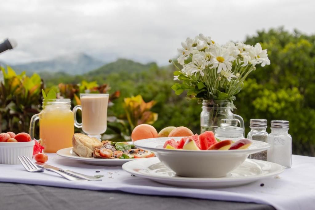 Un desayuno con una mesa, un jarrón de flores y una vista panorámica de fondo.