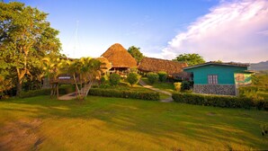 Un resort con edificios de techo de paja, una construcción de muros de piedra y un jardín bien cuidado.